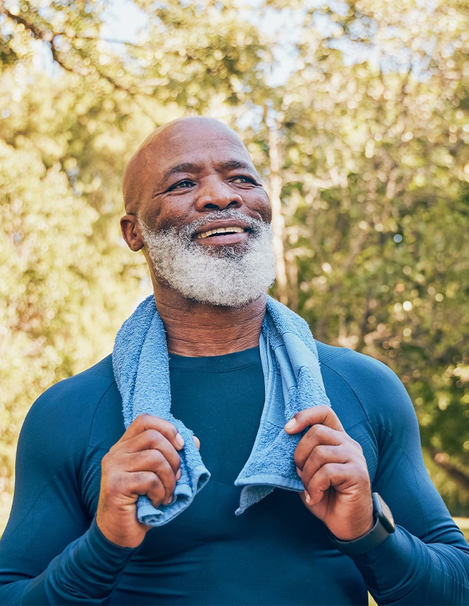 Smiling senior Black man with white beard holding towel around neck outdoors after exercise - PLDF in Carmel, IN