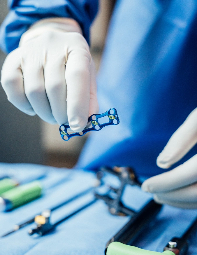 Surgeon in blue scrubs holding surgical instrument during medical procedure in operating room - Thoracic and lumber corepectomy in Carmel, IN