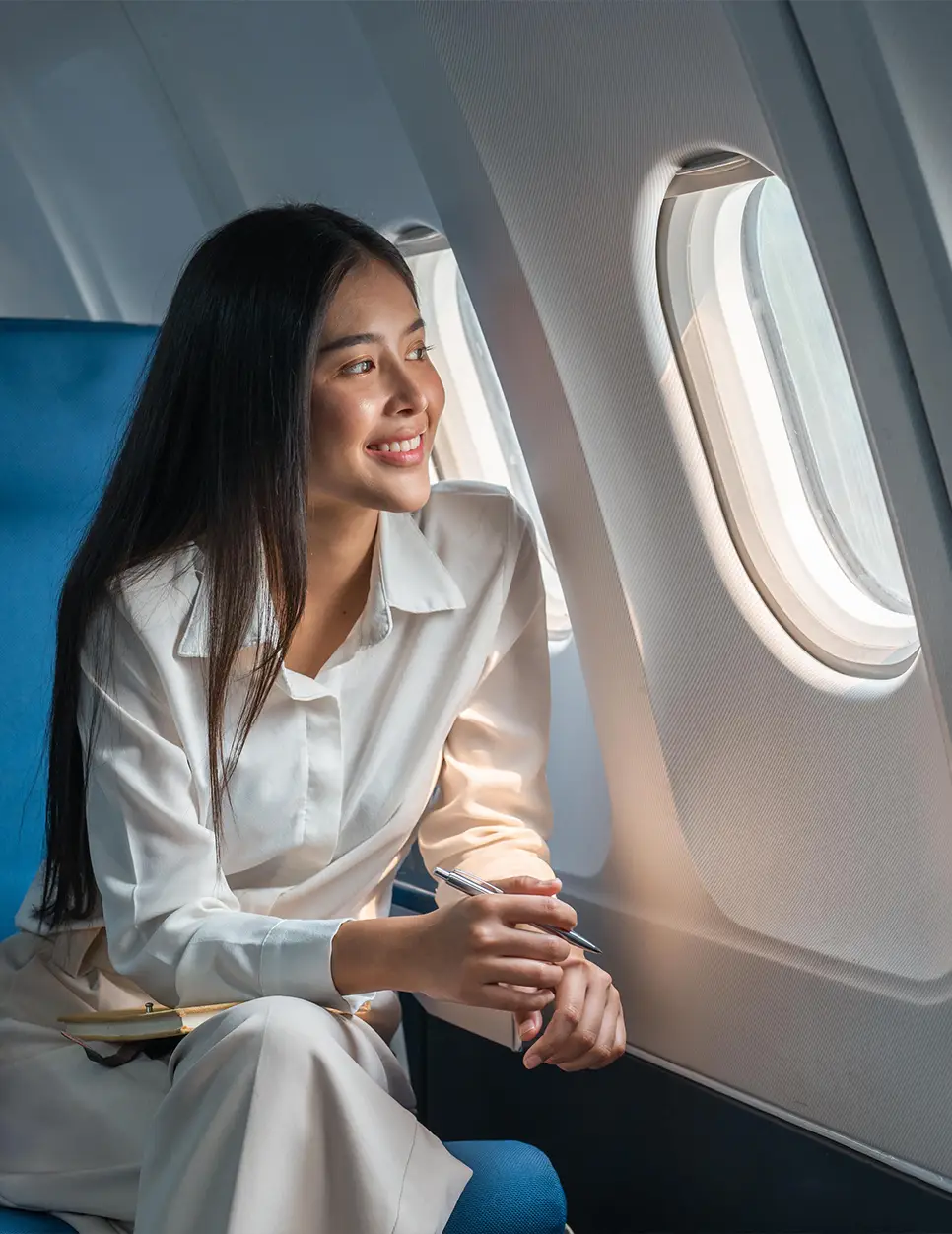 Woman in white business suit looking out airplane window during flight to medical appointment - Travel in Carmel, IN