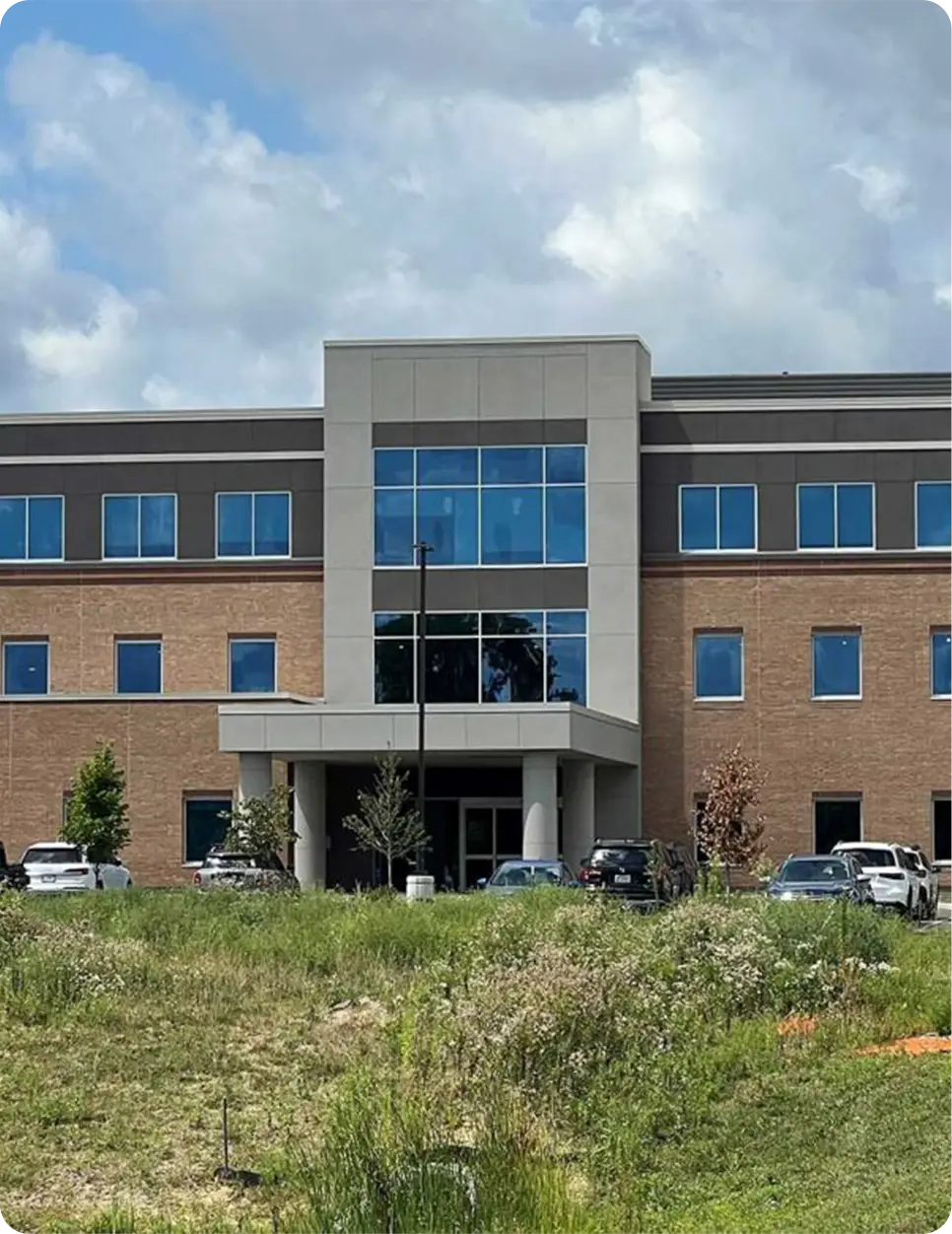 Modern brick office building with glass entrance in Carmel with cloudy sky and landscaped grounds